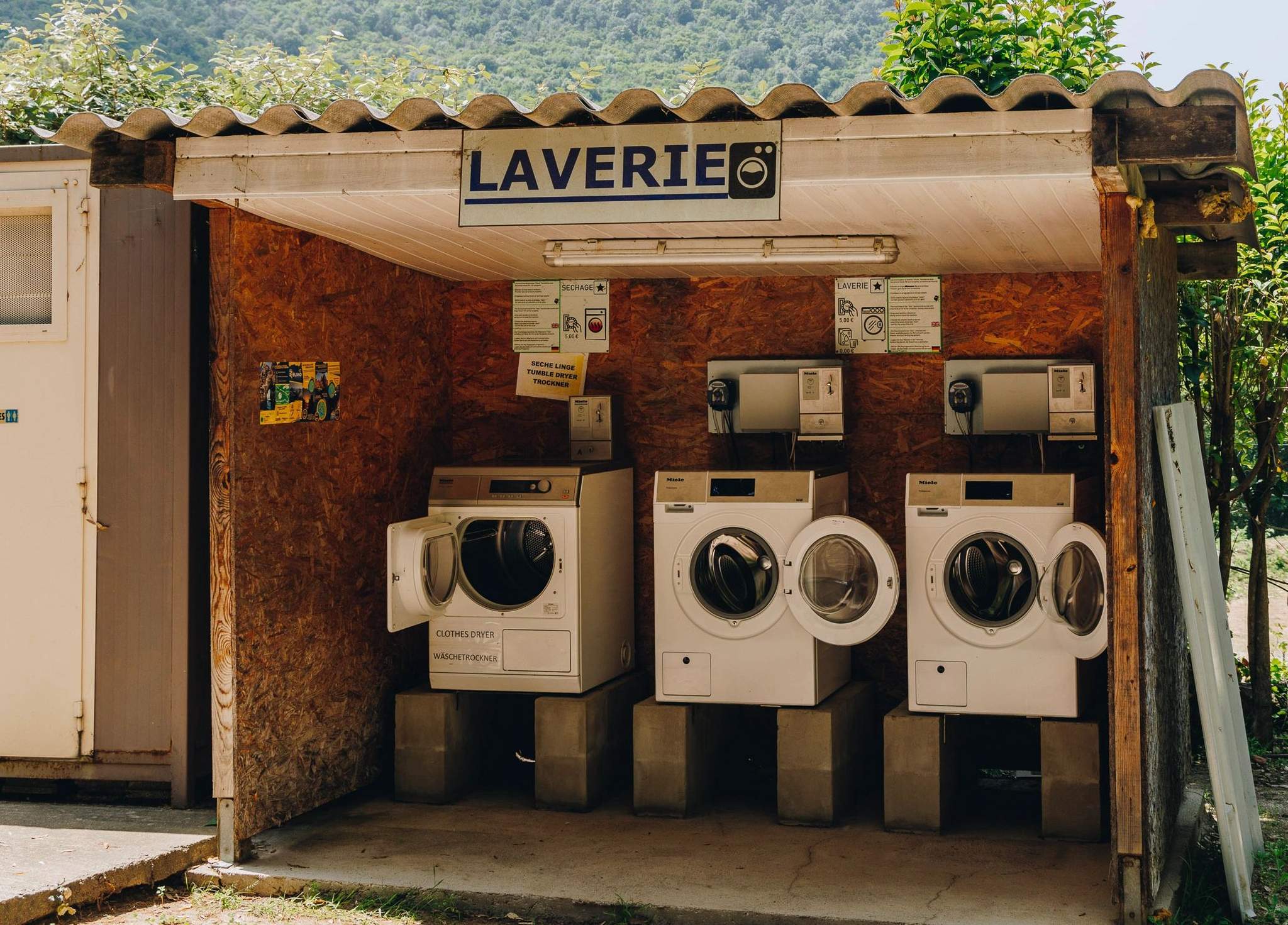 Laverie automatique d'un camping avec piscine proposant plusieurs machines à laver